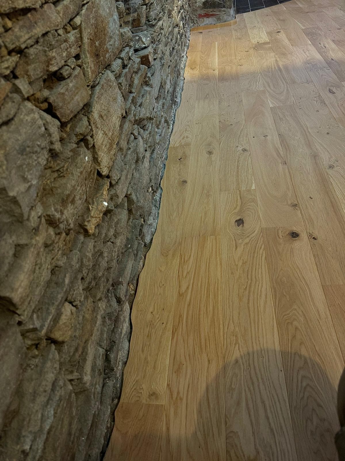 Parquet chêne large contre un mur en pierre